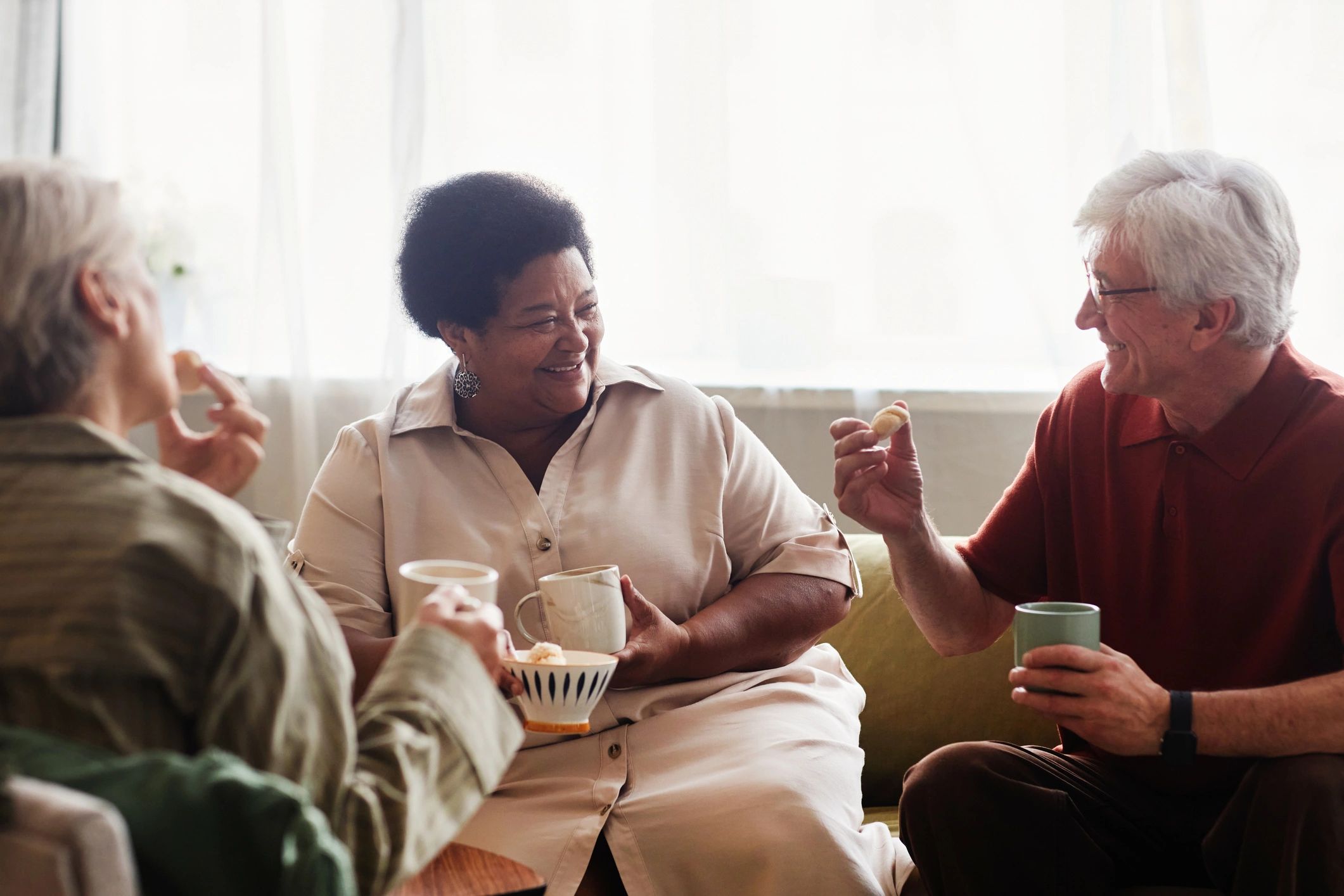 Senior people enjoying tea together at home in a supportive community setting