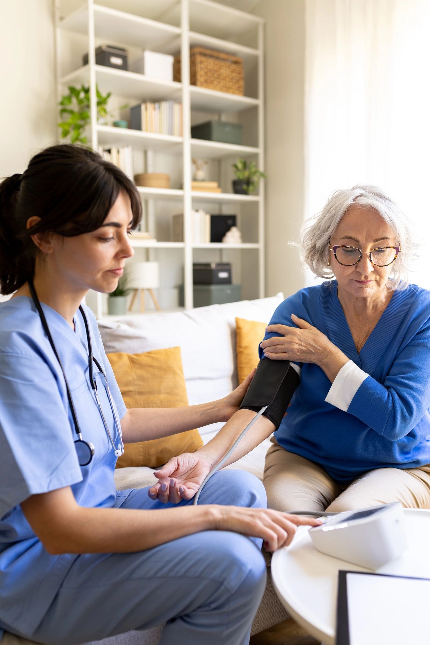 Nurse checking blood pressure of a senior woman at home